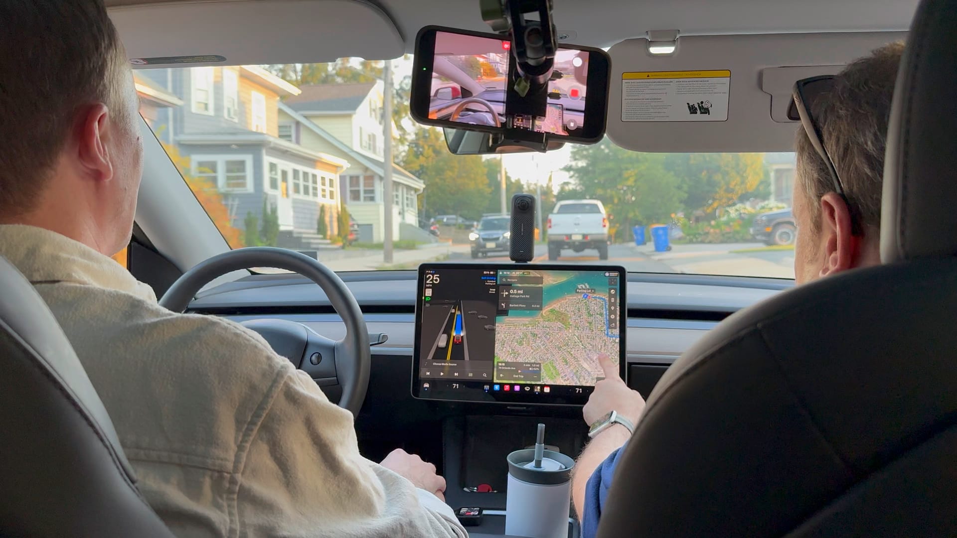 Moritz Keck at the wheel of a Tesla Model 3 during a Full Self-Driving ride, the center display showing the FSD visualization